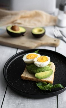 Avokado, domates ve haşlanmış yumurtalı sandviç. Tahta bir arka bahçede. Snidanok.