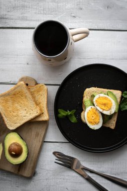 Avokado, domates ve haşlanmış yumurtalı sandviç. Tahta bir arka bahçede. Snidanok.