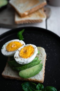 Avokado, domates ve haşlanmış yumurtalı sandviç. Tahta bir arka bahçede. Snidanok.