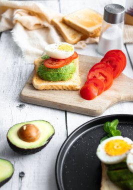 Avokado, domates ve haşlanmış yumurtalı sandviç. Tahta bir arka bahçede. Snidanok.