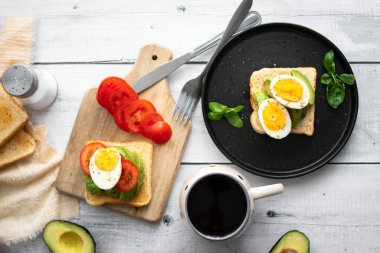 Avokado, domates ve haşlanmış yumurtalı sandviç. Tahta bir arka bahçede. Snidanok.