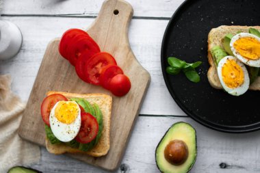 Avokado, domates ve haşlanmış yumurtalı sandviç. Tahta bir arka bahçede. Snidanok.