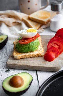 Avokado, domates ve haşlanmış yumurtalı sandviç. Tahta bir arka bahçede. Snidanok.