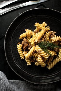 Siyah tabakta etli ve sebzeli makarna, yakın çekim.