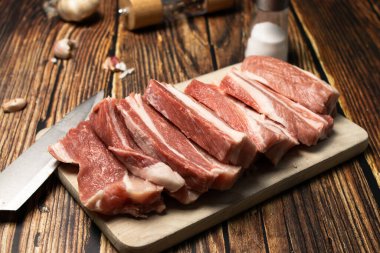 Kesme tahtasında çiğ domuz pirzolası ve sarımsak. Tahta bir masada. Yemek.