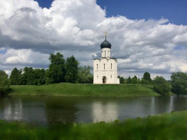 Beautiful view of the church by the river (Church of the Intercession on the Nerl, Vladimir, June) clipart