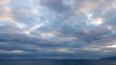 Gökyüzü seni ezmek üzere gibi görünüyor. Kıvırcık bulutlar denizin üzerinde asılı. Resim olarak deniz ve gökyüzü. Yalnızlığı ve önemsizliği hisset, gökyüzünde mavi ve sarı renkler (Baykal Gölü kıyısından manzara, Ekim)