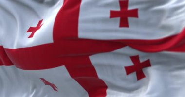 Gürcistan ulusal bayrağının rüzgarda dalgalanmasına yakın çekim görüntüsü. Gürcistan kıtalararası bir ülke. Kumaş desenli arka plan. Seçici odaklanma. Yavaş çekimde kusursuz döngü