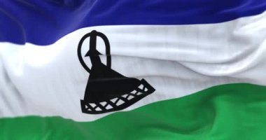 Lesotho ulusal bayrağının dalgalanmasına yakından bakın. Lesotho Krallığı, Afrika kıtasında bulunan bir devlettir. Kumaş desenli arka plan. Seçici odaklanma. Yavaş çekimde kusursuz döngü