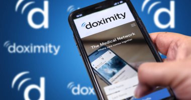 San Francisco, CA, ABD Mart 2022: Doximity şirketinin web sitesi telefon ekranında. Arka planda tekrarlanan Doximity logosu olan mavi arkaplan bulanıklaştı. İllüstrasyon başyazısı. Seçici odak.
