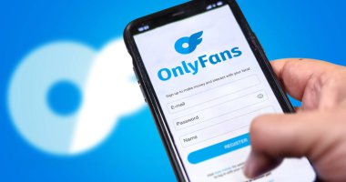Londra, İngiltere, Ağustos 2021; bir el ekranında OnlyFans kayıt formu olan bir cep telefonu tutuyor ve arka planda logo bulanıklaşıyor. Sadece Hayranlar bir internet içeriği abonelik hizmetidir