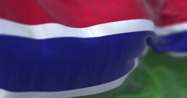 Perspective view of the Gambia national flag waving. Horizontal red, blue and green striped flag. Fluttering textile. Selective focus. 3d render animation. Slow motion loop