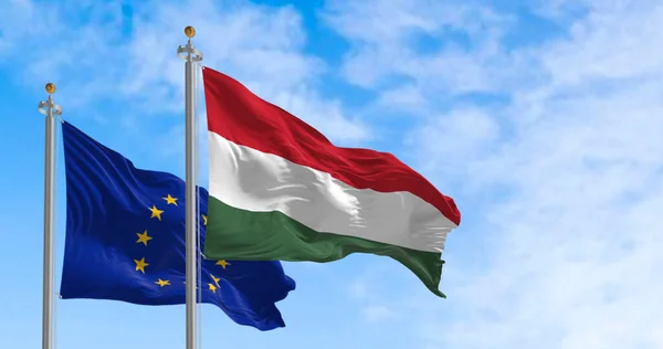 The flags of Hungary and the European Union fluttering together on a clear day. Hungary became a member of the European Union on 2004. 3d illustration render. International treaty and diplomacy