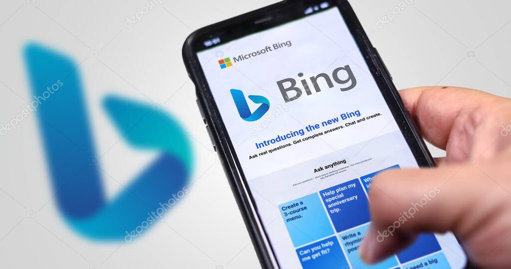 Redmond, US, Feb 2023: A hand holding a phone with the Microsoft Bing website on the screen. White background with blurred Bing logo. Bing is a search engine recently integrated with AI chatbot