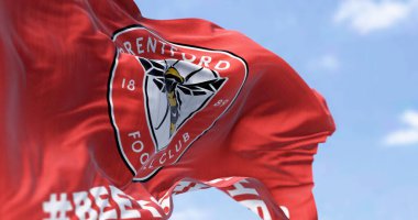 Londra, İngiltere, Şubat 2023: Brentford FC bayrağı dalgalanıyor. Kırmızı üzerinde arı olan dairesel bir amblem. Dalgalı kumaş arka planı. İllüstrasyon 3d illüstrasyon canlandırması. Seçici odaklanma. Yakın plan.