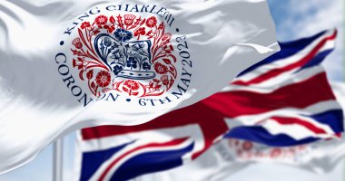 Kral III. Charles 'ın taç giyme töreninin amblemi olan bayraklar ve sallanan İngiliz bayrakları. Amblem, St. Edward Crown şeklindeki dört ulusun florasını tasvir ediyor. 3D illüstrasyon canlandırıcı. Dalgalanan tekstil