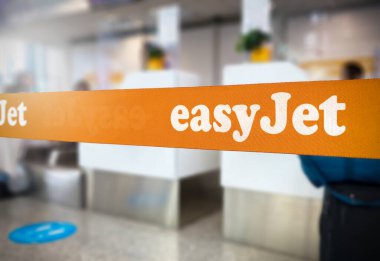Londra, Birleşik Krallık Jan 2023: Easyjet logosu havaalanının içinde olan turuncu geri çekilebilir kemer bariyeri. Easyjet, çok uluslu düşük maliyetli bir İngiliz havayolu şirketidir. Seyahat ve havaalanı güvenliği. İllüstrasyon Editörü