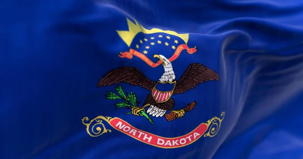 Close-up of North Dakota state flag waving. Blue with coat of arms. Eagle above scroll. 3d illustration render. Textured background. Selective focus. Fluttering textile