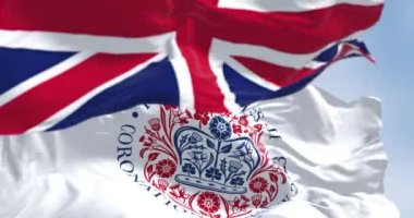 Londra, İngiltere, Nisan 2023: Kral III. Charles 'ın taç giyme töreninin amblemi olan bayraklar ve İngiltere el sallaması. Kusursuz 3 boyutlu animasyon. Yavaş çekim döngüsü. Seçici odaklanma. Kanat çırpan kumaş. Yakın plan.