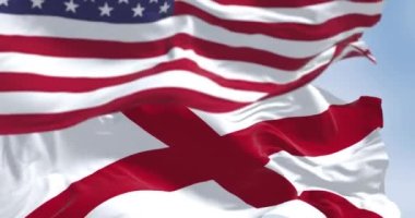 Birleşik Devletler ve Alabama bayrakları birlikte dalgalanıyor. Alabama bayrağında beyaz bir tarlada kırmızı bir haç var. Kusursuz 3 boyutlu animasyon. Yavaş çekim döngüsü. Seçici odaklanma. Kanat çırpan kumaş. Yakın plan.