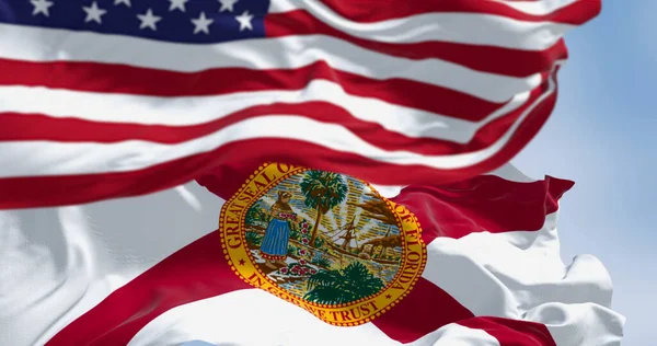 The flags of Florida and United States waving in the wind on a clear day. Florida is a state in the southeastern US. US federate state. 3d illustration render. Selective focus. Fluttering textile