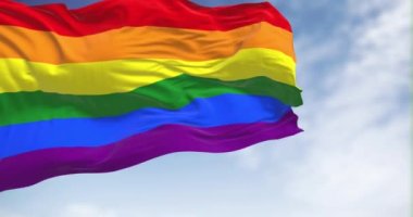 Gökkuşağı bayrağı açık havada dalgalanıyor. Gökkuşağı renkli çizgili bayrak, genellikle LGBT gururunun sembolü olarak kullanılır. 3D canlandırma canlandırması. Yavaş çekim döngüsü. Seçici odaklanma. Kanat çırpan kumaş. Yakın plan.