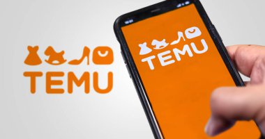 Boston, ABD, Mart 2023: Ekranda Temu logosu sergilenen bir telefon elindeydi. Arka planda bulanık logo var. Temu çevrimiçi bir pazar yeri. İllüstrasyon Editörü