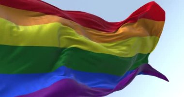 Gökkuşağı bayrağı açık havada dalgalanıyor. LGBT gururunun sembolü olarak çok renkli bayrak kullanılır. Kusursuz 3 boyutlu animasyon. Yavaş çekim döngüsü. Kanat çırpan kumaş. Yakın plan. 4k