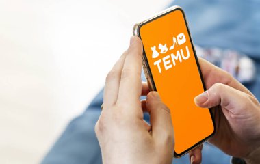 Boston, ABD, Mart 2023: Temu logosu ekranda gösterilen telefonu tutan kadın elleri. Temu çevrimiçi bir pazar yeri. İllüstrasyon Editörü