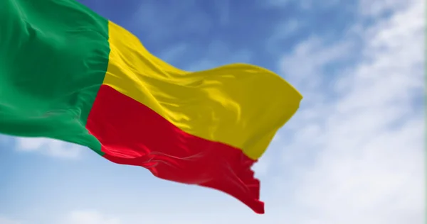 stock image National flag of Benin waving on a clear day. Two horizontal yellow and red bands on the fly side and a green vertical band at the hoist. 3d illustration render. Fluttering fabric. Selective focus