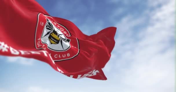 2023年2月19日 布伦福德足球俱乐部的旗帜在晴朗的日子飘扬 圆圆的徽章 里面有一只蜜蜂在红色上 无缝3D渲染动画 慢动作回圈有选择的重点 — 图库视频影像