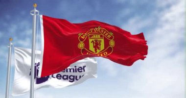 Manchester, İngiltere, 2 Temmuz 2023: Manchester United FC ve Premier League bayrakları açık bir günde dalgalanıyor. Kusursuz 3 boyutlu animasyon. Yavaş çekim döngüsü. Kanat çırpan kumaş. 4k