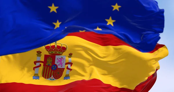 National flag of Spain waving with the European Union flag in the background on a clear day. International cooperation. 3d illustration render. Rippled fabric. Selective focus