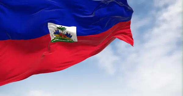 Haiti national flag waving in the wind on a clear day. Two horizontal bands of blue and red with national coat of arms in a small white rectangle in the center. 3d illustration render. Rippling fabric