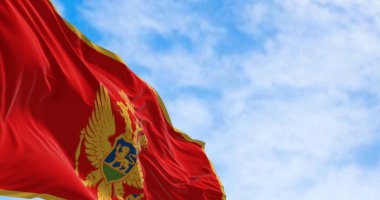 Karadağ 'ın ulusal bayrağı açık bir günde rüzgarda sallanıyor. Altın kenarlı kırmızı ve ulusal armanın merkezinde yer alıyor. 3D illüstrasyon canlandırıcı. Seçici odaklanma. Çırpınan kumaş