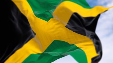 Açık bir günde Jamaika ulusal bayrağının dalgalanması. Altın taşlama iki yeşil ve iki siyah olmak üzere dört parçaya bölünmüş. 3D illüstrasyon canlandırıcı. Kanat çırpan kumaş. Seçici odak