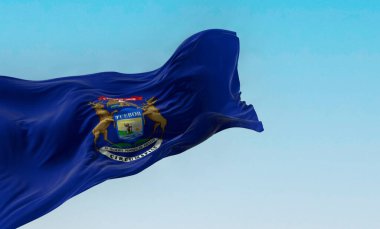 Michigan eyalet bayrağı açık havada rüzgarda sallanıyor. Üzerinde bir kartal, bir geyik ve bir geyik bulunan koyu mavi bir bayrak. 3D illüstrasyon canlandırıcı. Dalgalanan kumaş