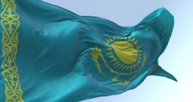 Açık bir günde Kazakistan ulusal bayrağının yakın çekimi. Açık mavi tarla, sarı güneş, ortasında uçan kartal ve sarı süslemeli bir bant. Kusursuz 3D canlandırma döngüsü. Yavaş çekim