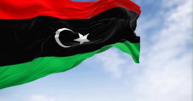 Açık bir günde Libya bayrağı sallanıyor. Kırmızı, siyah, yeşil çizgiler; beyaz yıldız ve siyah üzerine hilal. 3D illüstrasyon canlandırıcı. Dalgalanan kumaş. Seçici odaklanma. Sallanan bayrak