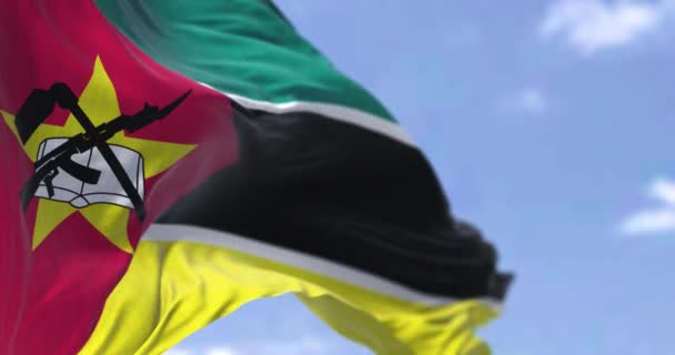 モザンビークの国旗は 自由と希望を象徴する部分的に曇った空に対する独特のエンブレムを特徴としています シームレス3Dレンダリングアニメーション スローモーションループ 選択的なフォーカス — ストック動画
