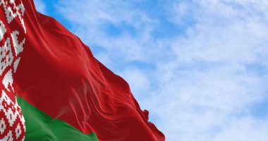 Açık bir günde rüzgarda sallanan Belarus bayrağının yakın çekimi. Beyaz ve kırmızı süslemeli kırmızı ve kırmızı bayrak. Personel bitiş çizimine yerleştirilmiş. Dalgalanan tekstil