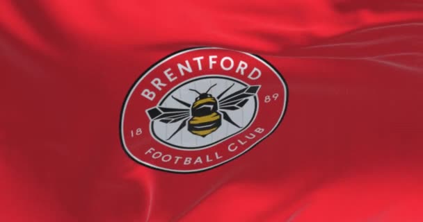 2023年2月19日 布伦福德足球俱乐部 Brentford Football Club 的特写挥动旗帜 圆圆的徽章 里面有一只蜜蜂在红色上 无缝3D渲染动画 慢动作回圈飘扬的旗帜 — 图库视频影像