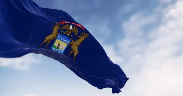 Michigan state flag waving in the wind on a clear day. Dark blue flag with state coat of arms featuring an eagle, an elk and a moose. 3d illustration render. Rippling fabric. Selective focus