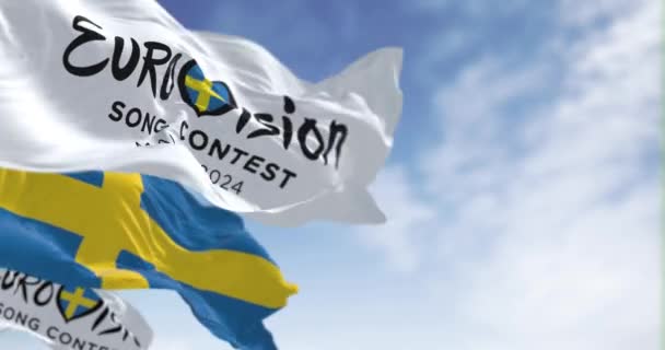 2023年10月25日 ユーロビジョン ソング コンテスト2024とスウェーデン国旗が晴れた日 シームレス3Dレンダリングアニメーション スローモーションループ 選択的な焦点 ウィングフラッグ — ストック動画
