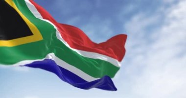 Güney Afrika bayrağının yakın çekimi. Kırmızı ve mavi bayrak, sarı kenarlı siyah üçgeni çevreleyen yeşil Y ile bölünmüş. Kusursuz 3 boyutlu animasyon. Yavaş çekim döngüsü. Seçici odak