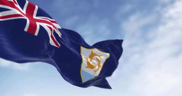 晴れた日に風に揺れるアンギラの旗 ブルー エンサイン カントンのイギリスの国旗 武器のコート 3つのイルカが白い盾の上にあります シームレス3Dレンダリングアニメーション スローモーションループ 選択的なフォーカス — ストック動画