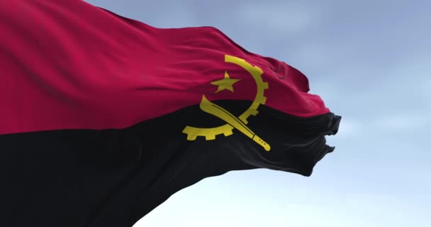 アンゴラの国旗が晴れた日に風を吹いている 2つの水平バンド 赤と黒 中央に黄色のエンブレム シームレス3Dレンダリングアニメーション スローモーションループ — ストック動画