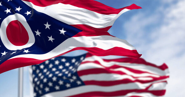 The Ohio state flag waving with the national flag of the United States of America on a clear day. 3D illustration render. Rippled textile. Selective focus