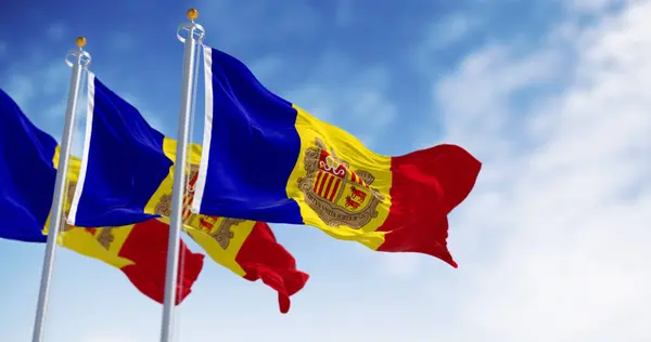 stock image Flags of the Principality of Andorra waving in the wind on a clear day. Vertical blue-yellow-red stripes with coat of arms in center. 3d illustration render. Rippled fabric.