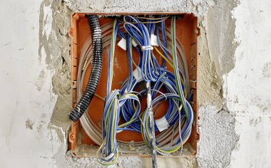 Renklendirici kablolar ve kurulum detaylarını gösteren, yenilenme sırasında bir duvarın içindeki açık elektrik kablolarının ve kanalların yakın görüntüsü